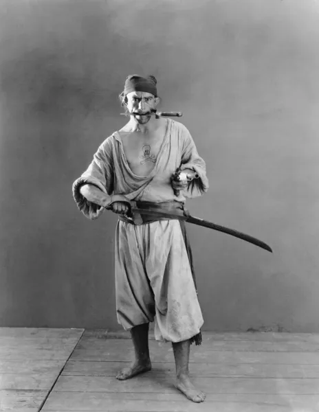 Retrato de un pirata sosteniendo una espada y una pistola en sus manos con un cuchillo en la boca —  Fotos de Stock