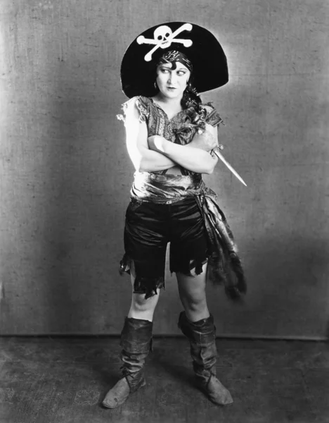 Feminino em um traje de pirata de pé com os braços cruzados e segurando uma faca — Fotografia de Stock