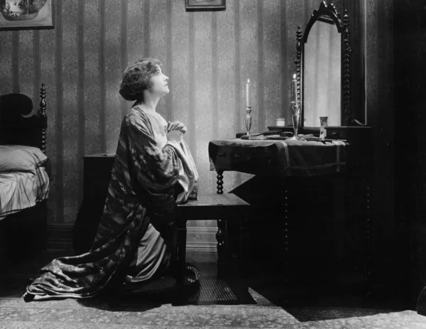 Perfil de uma jovem implorando na frente de um espelho em seu quarto de cama — Fotografia de Stock