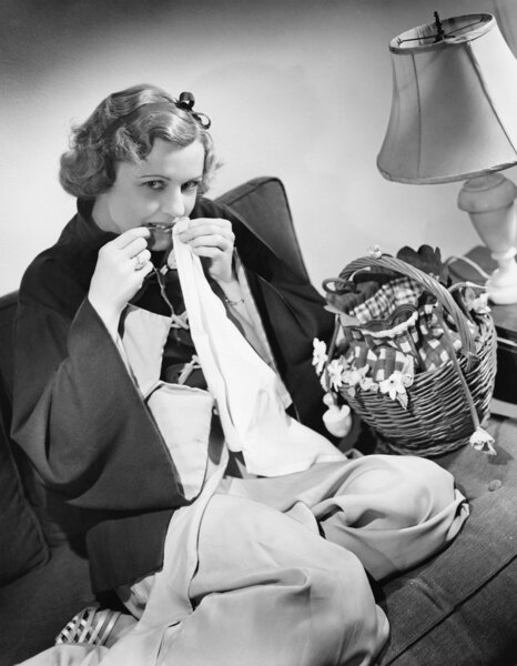 Portrait of a young woman cutting thread with her teeth