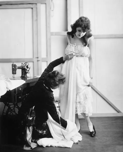 Perfil de uma alfaiate fêmea tomando medidas de uma jovem mulher em uma loja de noivas — Fotografia de Stock
