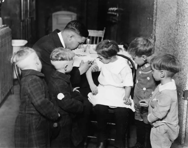 Barnläkare immuniseringsämnet en liten flicka medan andra barn tittar på — Stockfoto