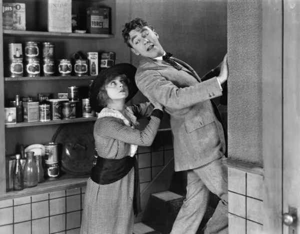 Perfil de uma jovem mulher empurrando um jovem de uma cozinha doméstica — Fotografia de Stock
