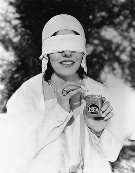 Młoda kobieta z oczami zawiązanymi oczami biorąc pod uwagę papierosa z paczki papierosa — Zdjęcie stockowe