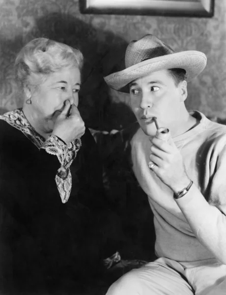 Ung man röka en pipa med en kvinna med hennes näsa — Stockfoto
