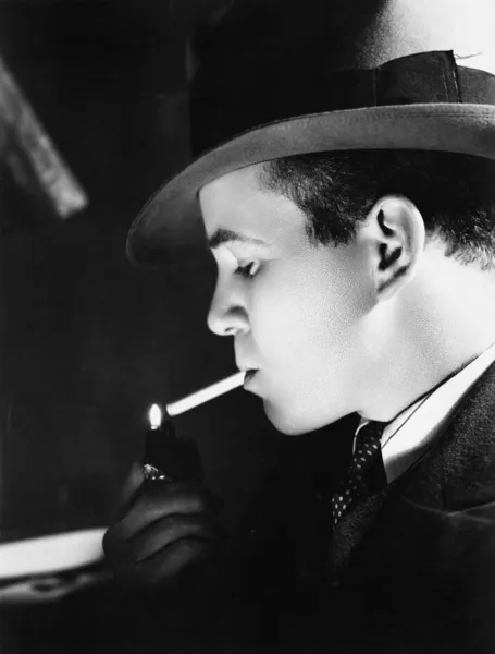 Zbliżenie: młody mężczyzna w kapeluszu, oświetlenie papierosa z gniazda zapalniczki — Zdjęcie stockowe