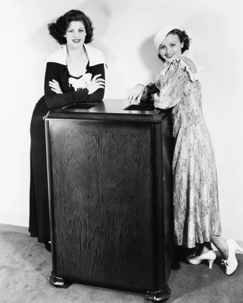 Porträt zweier junger Frauen, die sich an eine Klimaanlage lehnen — Stockfoto