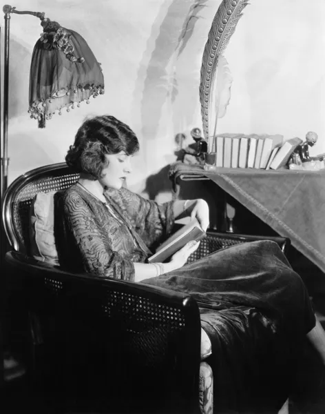 Profil młoda kobieta siedzi na fotelu i czytanie książek — Zdjęcie stockowe
