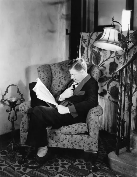 Egy férfi ül a karosszékben, és egy könyvet olvas profilja — Stock Fotó