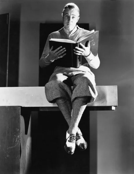 Porträt eines Mannes, der auf einer Holzplanke sitzt und ein Buch hält — Stockfoto