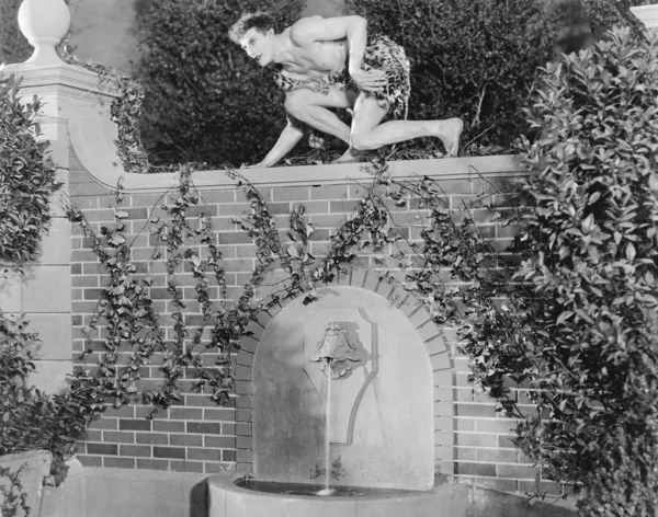 Perfil de un joven agachado en una pared — Foto de Stock