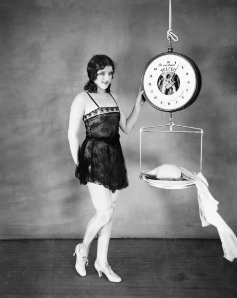 Retrato de uma jovem mulher pesando suas roupas em uma balança — Fotografia de Stock