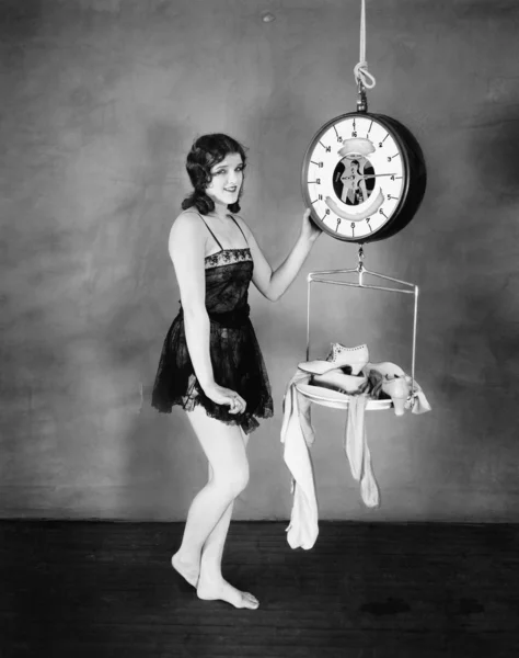 Retrato de uma jovem pesando suas roupas e sandálias em uma balança — Fotografia de Stock