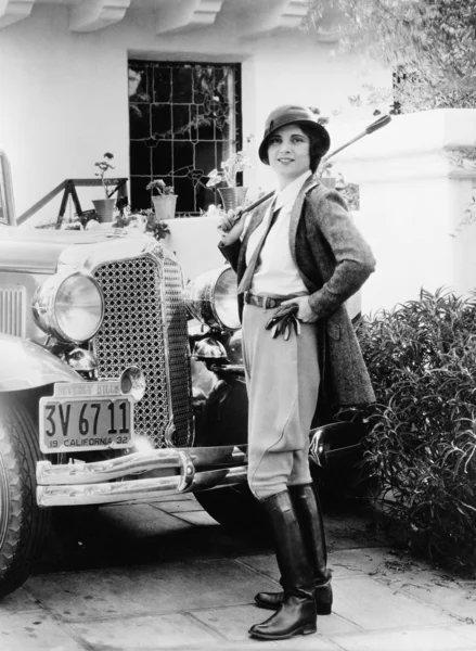 Porträtt av en kvinna framför hennes bil i en ridning outfit — Stockfoto
