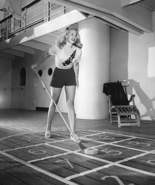 Młoda kobieta gra shuffleboard — Zdjęcie stockowe