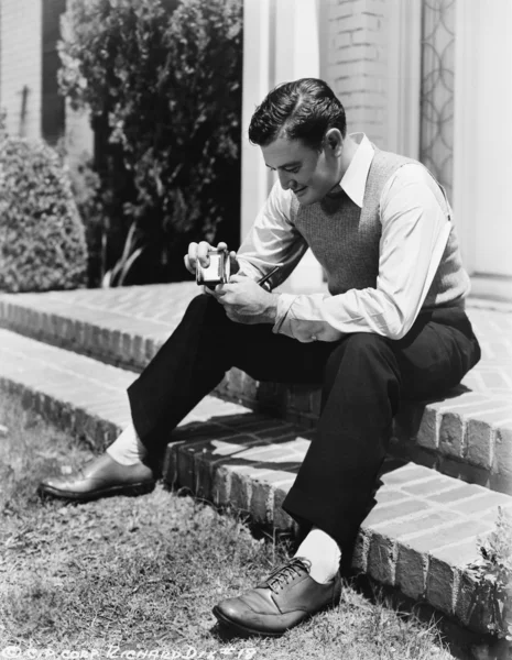 Νεαρός άνδρας κάθεται σε ένα βήμα και κρατώντας ένα αναπτήρα με ένα σωλήνα — Φωτογραφία Αρχείου