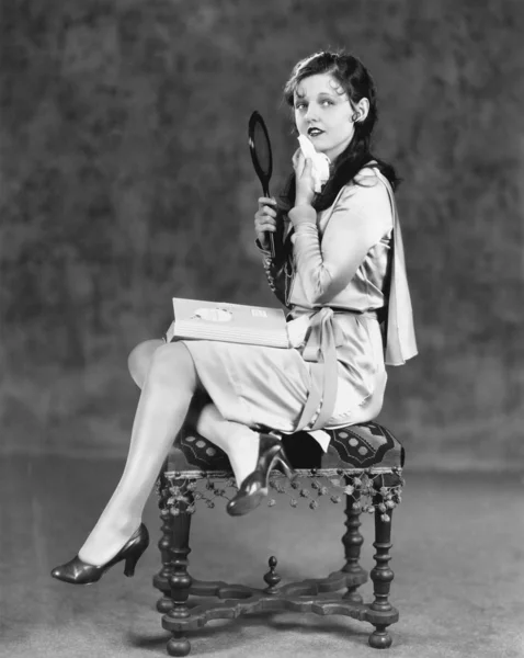 Mladá žena sedí na stoličce drží zrcadlo vanity — Stock fotografie