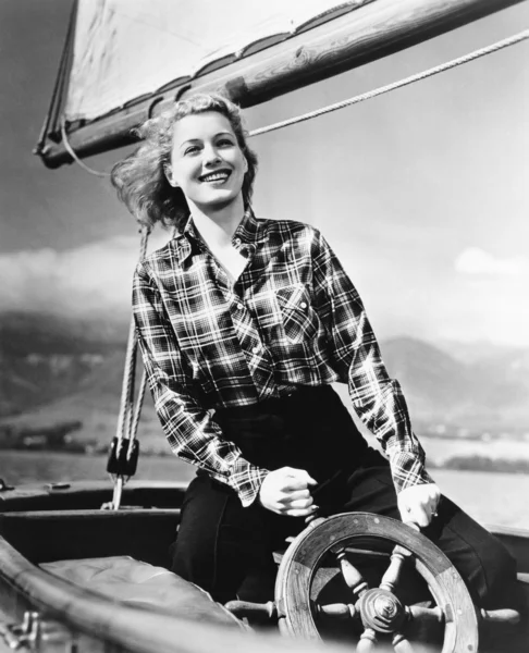Joven mujer de pie al timón de un velero y sosteniendo la rueda — Foto de Stock
