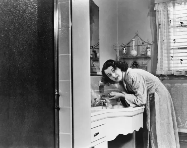 Profiel van een jonge vrouw die haar handen in de badkamer wastafel wassen — Stockfoto