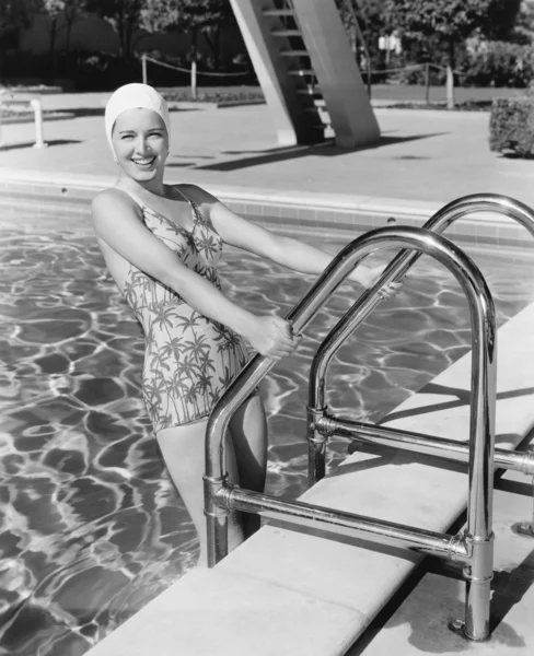 Giovane donna che sale la scala di una piscina — Foto Stock