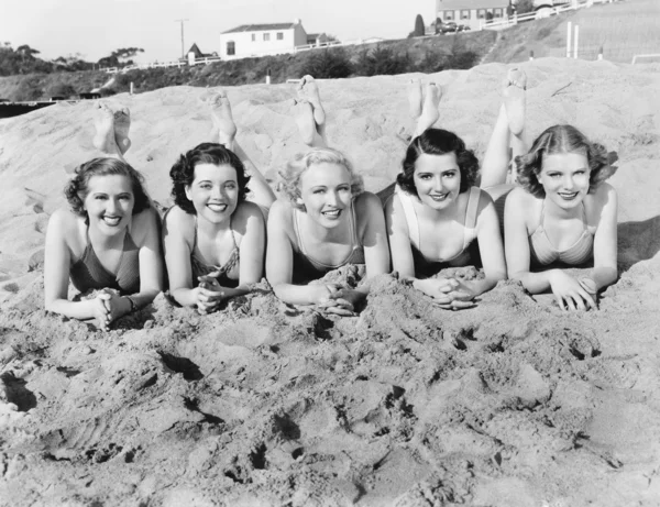Retrato de cinco jóvenes tumbadas en la playa y sonrientes —  Fotos de Stock