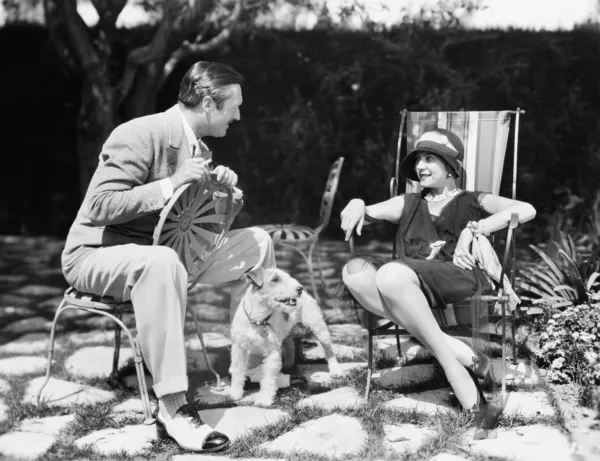 Casal sentado no quintal falando com um cão entre eles — Fotografia de Stock