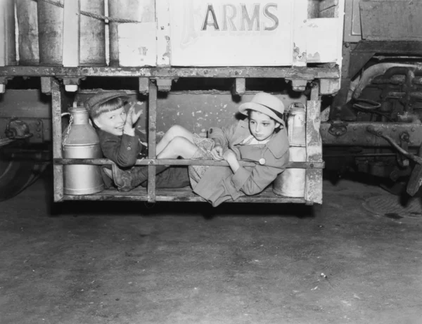 Two boys with milk canisters in a cargo bay of a truck — Stock Photo, Image