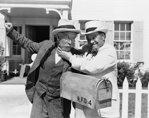 Δύο ώριμη άνδρες αγωνίζονται κοντά σε ένα ταχυδρομικό κουτί μπροστά από ένα σπίτι — Φωτογραφία Αρχείου