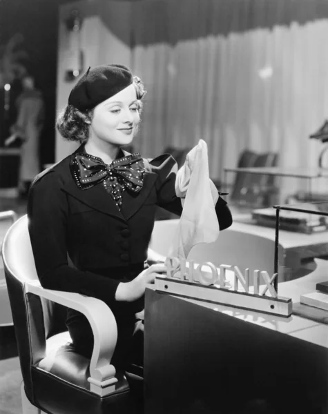 Giovane donna seduta in un grande magazzino e in possesso di calze — Foto Stock