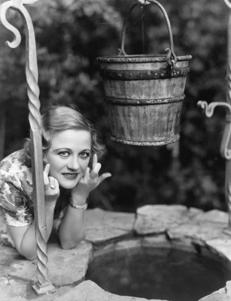 Portrait of a woman leaning on a well with her finger crossed — Stock Photo, Image