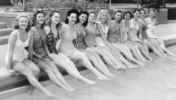 Gruppo di donne sedute di fila a bordo piscina — Foto Stock
