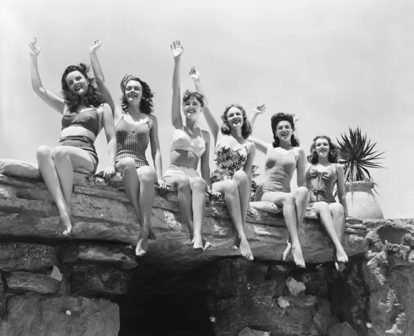 Vista de bajo ángulo de un grupo de mujeres sentadas en una estructura de piedra y agitando sus manos — Foto de Stock