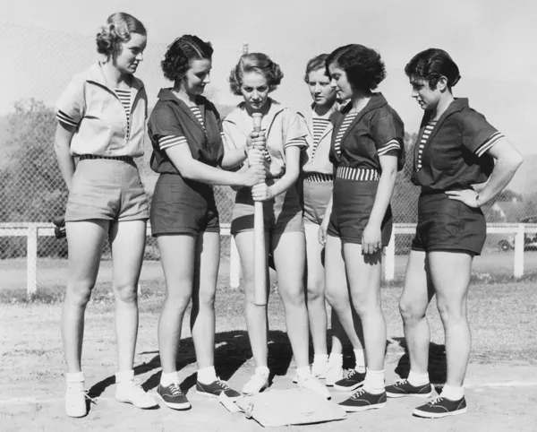 Mujer sosteniendo un bate de béisbol y dando entrenamiento a otras mujeres — Foto de Stock