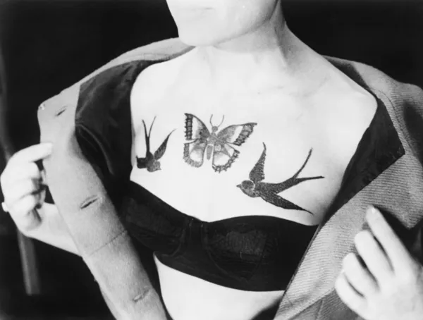 Närbild av en kvinna som visar tatueringar på hennes bröst — Stockfoto