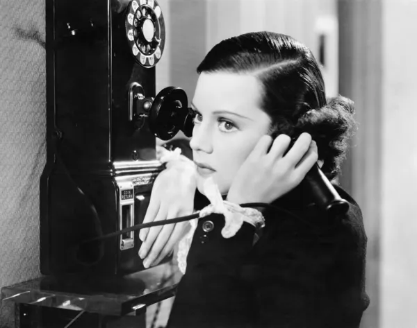 Perfil de una joven hablando por teléfono público — Foto de Stock