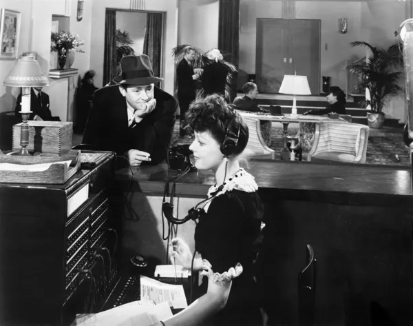 Perfil de una mujer que trabaja en la centralita telefónica con un hombre mirándola — Foto de Stock