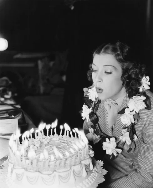 Profil młoda kobieta nadmuchowy świeczki na tort urodzinowy — Zdjęcie stockowe
