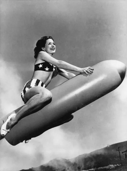 Visão de baixo ângulo de uma jovem mulher sentada em um foguete e sorrindo — Fotografia de Stock