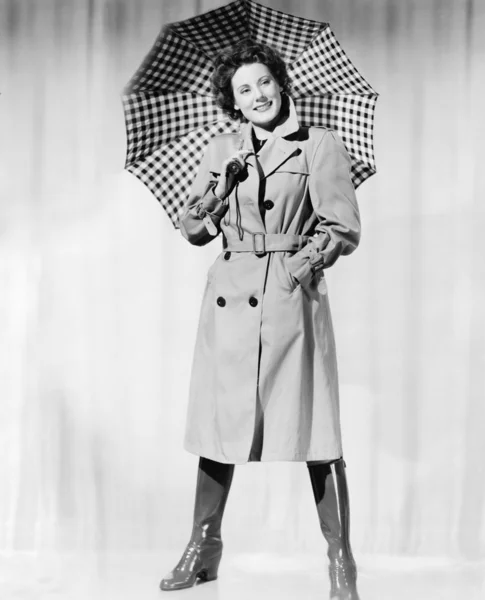 Женщина в дождевой экипировке держит зонтик и улыбается — стоковое фото