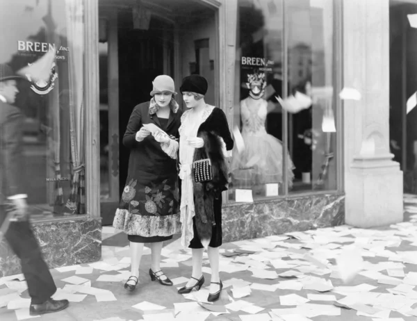 Zwei Frauen, die auf der Straße Zeitungen lesen, werden aus einem Büro geworfen — Stockfoto