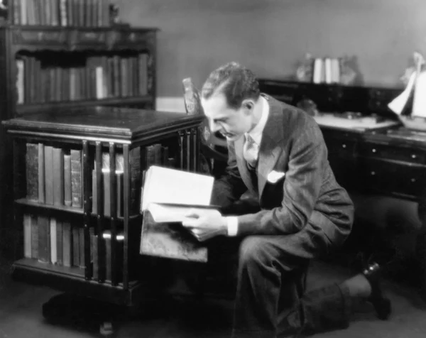 Человек в домашней библиотеке с книгой — стоковое фото