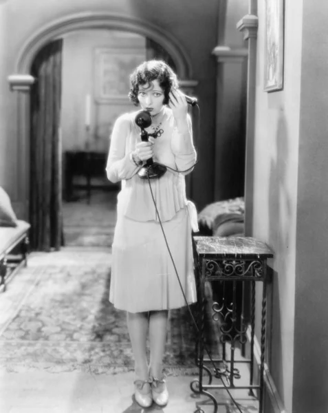Kobieta stojąc w korytarzu mówić na telefoniczne Świecznik — Zdjęcie stockowe