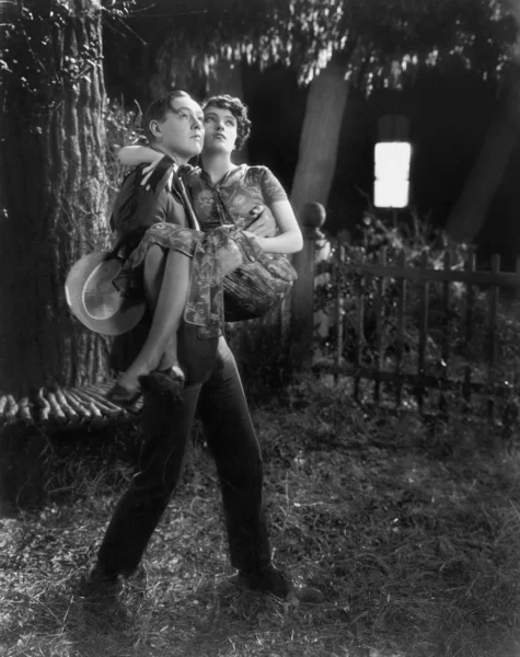 Hombre cargando a una mujer en sus brazos a través de un patio trasero — Foto de Stock