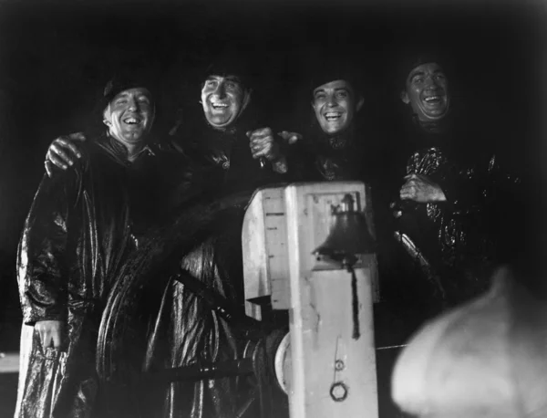 Τέσσερις άνδρες στο slickers που στέκονται μαζί με το τιμόνι του καπετάνιου ενός πλοίου — Φωτογραφία Αρχείου