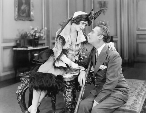 Woman sitting on a table and talking to a man on crutches