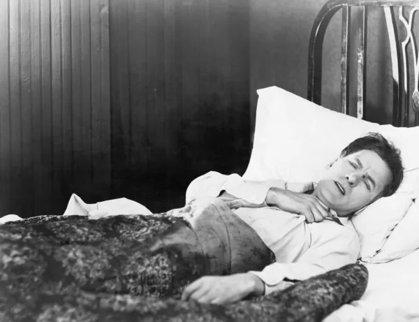 Homem deitado na cama segurando sua garganta com dor — Fotografia de Stock