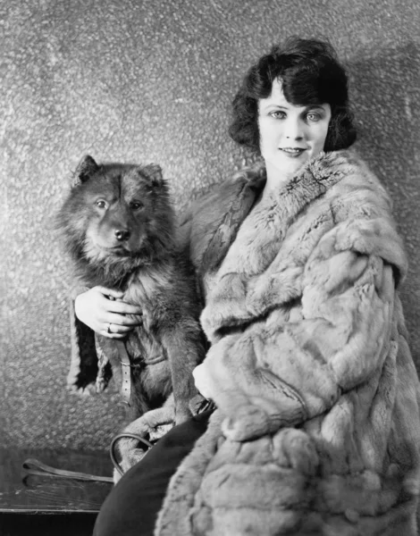 Kvinnan i hennes päls som sitter med sin hund — Stockfoto