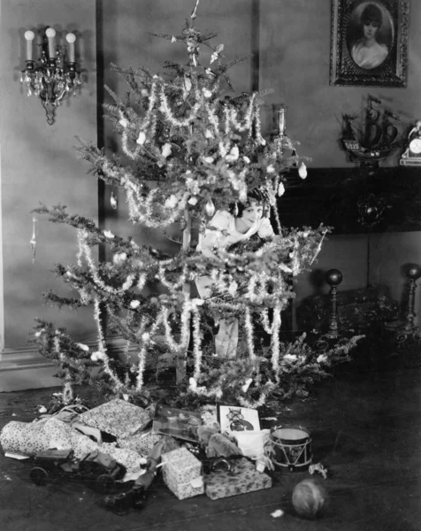 Vrouw verbergen in een versierde kerstboom — Stockfoto