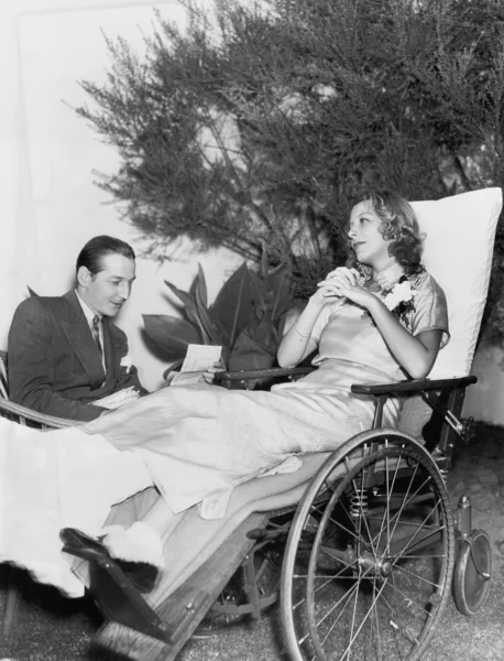 Женщина в инвалидном кресле слушает мужчину, читающего письмо — стоковое фото