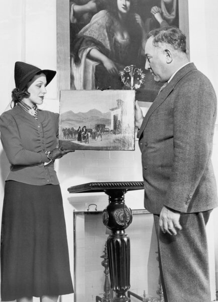 Женщина показывает пожилому мужчине произведение искусства
